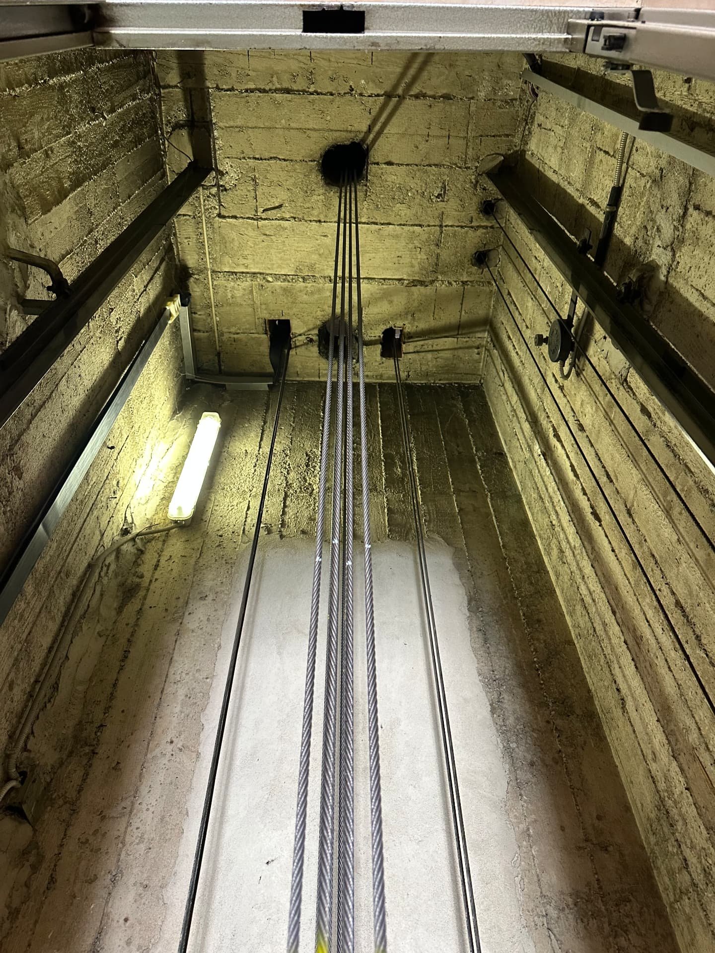 Fossa ascensore verniciata e vano corsa con funi e guide dopo l'intervento di manutenzione