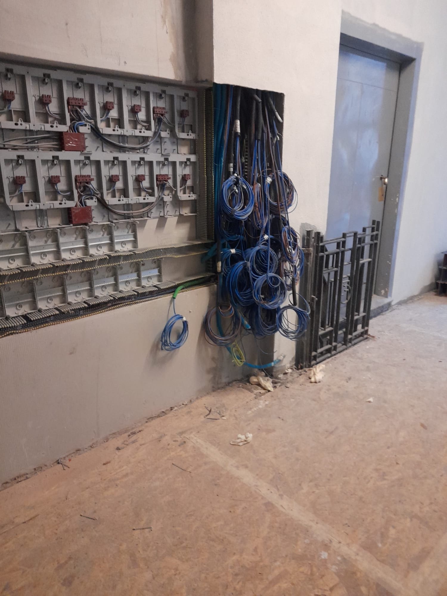 Cantiere elettrico con matasse di cavo blu e quadro in fase di cablaggio